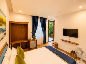 a hotel room with a bed and a flat screen tv at Metta Living Hoi An in Thanh Ðông (1)