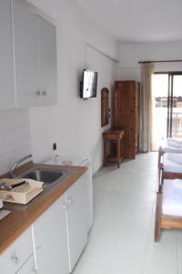 a white kitchen with a sink and a tv on the wall at Solis Apartments in Kallithea Halkidikis +7 photos