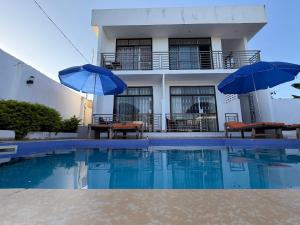 a house with two umbrellas and a swimming pool at La luna di zanzibar in Kiwengwa