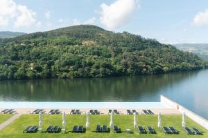 a pool with chairs and a view of a lake at Douro Royal Valley Hotel & Spa in Riba Douro