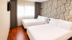a hotel room with two beds and a window at Hotel Apartamentos San Fermín Pamplona in Pamplona