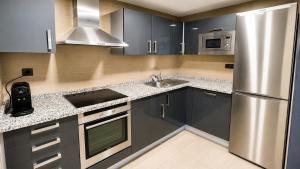 a kitchen with gray cabinets and a stainless steel refrigerator at Hotel Apartamentos San Fermín Pamplona in Pamplona