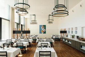 a restaurant with white tables and chairs and chandeliers at Douro Royal Valley Hotel & Spa in Riba Douro