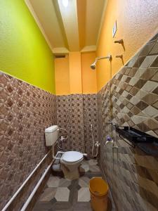 a bathroom with a toilet and a green and yellow wall at Sundarban Residential Hotel in Pātharpratima Island