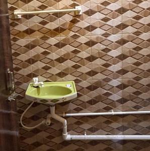a bathroom with a green sink on a tiled wall at Sundarban Residential Hotel in Pātharpratima Island