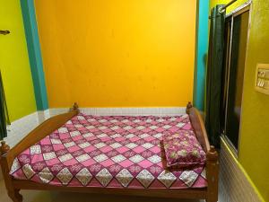 a bed in a room with a yellow wall at Sundarban Residential Hotel in Pātharpratima Island +2 photos