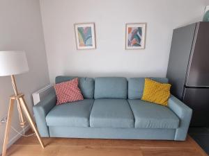 a blue couch in a living room with two colorful pillows at T2 Suresnes Proche La Défense Paris Parking Fibre in Suresnes