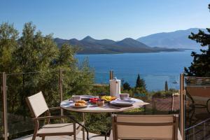 a table with food on a balcony with a view of the water at EOS Luxury Villa in Nydri +33 photos