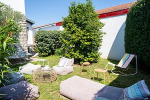 a garden with chairs and a couch and a hedge at Maison Cosy Bohème Chic Biarritz in Biarritz