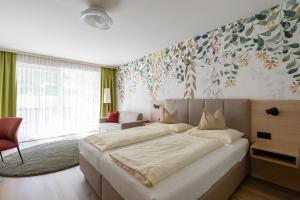 a bedroom with a large bed with a flower mural on the wall at Seehotel Vinzenz in Velden am Wörthersee