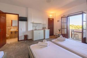 a room with two beds and a kitchen with a window at Alkyoni Forest Rooms in Skala