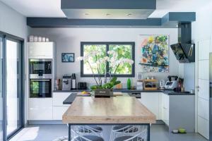 a kitchen with white cabinets and a large wooden table at Chambre D'hôtes Villa Menta in Arbonne