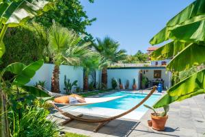 a hammock by a pool in a backyard with palm trees at Chambre D'hôtes Villa Menta in Arbonne