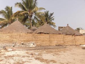 a brick wall with straw umbrellas and palm trees at Lasofia in Mbodiène
