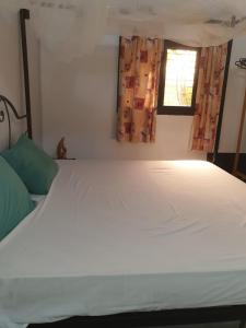 a bedroom with a large white bed with a window at Lasofia in Mbodiène