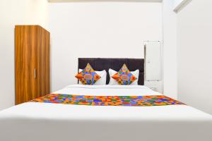 a bedroom with a large white bed with colorful pillows at Via Mannat in Indore +28 photos