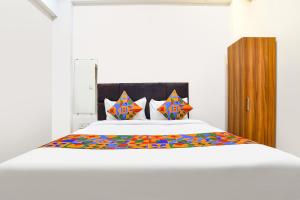 a bedroom with a white bed with colorful sheets and pillows at Via Mannat in Indore