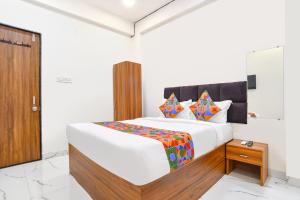 a bedroom with a large white bed and a wooden door at Via Mannat in Indore