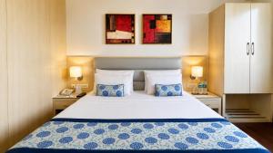 a bedroom with a large bed with two blue pillows at The Theme, Jaipur in Jaipur