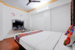 a white bedroom with a bed and a tv at FabHotel Raj in Pune