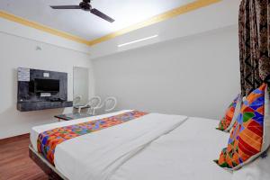 a white bedroom with a bed and a fireplace at FabHotel Raj in Pune
