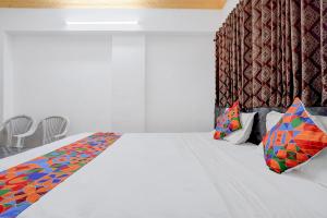 a bedroom with a large white bed with colorful pillows at FabHotel Raj in Pune