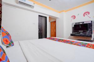 a white bedroom with a bed and a fireplace at FabHotel Raj in Pune