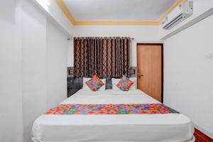 a bedroom with a large white bed with colorful pillows at FabHotel Raj in Pune +23 photos
