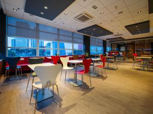 a restaurant with tables and chairs and large windows at ibis Mogi das Cruzes Shopping in Mogi das Cruzes