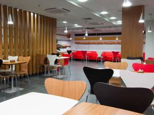 a restaurant with tables and chairs and red chairs at ibis Cascavel in Cascavel