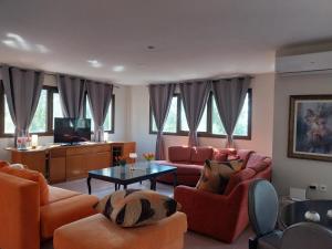 a living room with orange furniture and a tv at FANTASY GRAND VILLA THASSOS in Astris