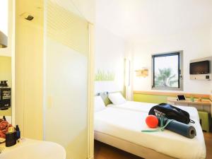 a hotel room with a bed with a bag on it at Ibis Budget Sevilla Aeropuerto in Seville