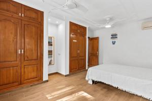 a white bedroom with wooden cabinets and a bed at Villa Casa Para Ti in El Tosalet