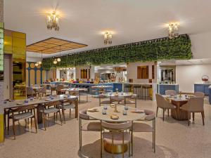 a restaurant with tables and chairs and a kitchen at Adagio Abu Dhabi Al Bustan in Abu Dhabi
