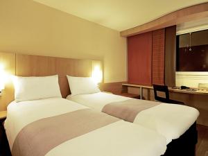ein Hotelzimmer mit zwei Betten und einem Schreibtisch in der Unterkunft ibis Delémont in Delémont