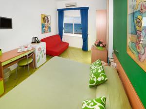 een kamer met een bed, een bureau en een rode bank bij Alta Marea Sorrento in Massa Lubrense