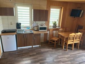 a kitchen with wooden cabinets and a table with a microwave at Domki pod Beskidem in Jaworzynka