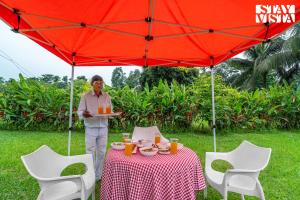 a man holding a plate of food under a red umbrella at StayVista at The Sahib's Bungalow with BBQ & Bonfire in Kālchīni +21 photos