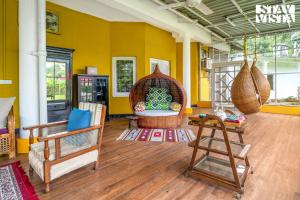 a living room with yellow walls and rattan furniture at StayVista at The Sahib's Bungalow with BBQ & Bonfire in Kālchīni