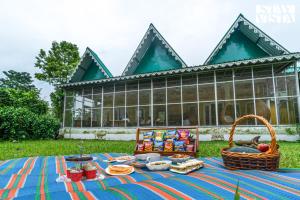 a picnic in the grass in front of a building at StayVista at The Sahib's Bungalow with BBQ & Bonfire in Kālchīni