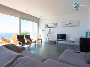 a living room with a couch and chairs and a television at Villa Sa Troneta in Cala Pi