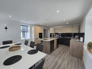a large kitchen with white tables and chairs at Woodside House in Crook of Alves