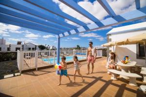 a man and two children playing with a ball on a patio at Villas & Apartamentos Tao Mazo in Lajares