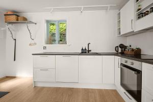 a white kitchen with white cabinets and a window at Hagehuset in Kragerø