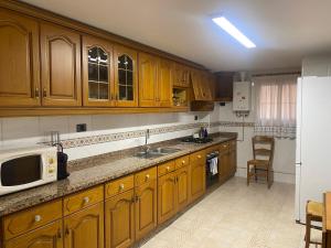 a kitchen with wooden cabinets and a sink and a microwave at Ca La Solé in Vinarós