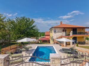 a pool with chairs and umbrellas in front of a house at Ivana in Karpijan in Umag