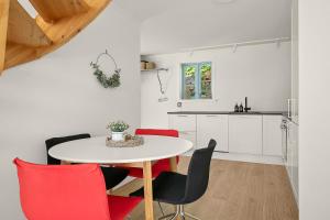 a white kitchen with a table and red chairs at Hagehuset in Kragerø
