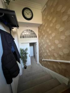 a hallway with a clock on the wall and stairs at West End Beds in Dundee