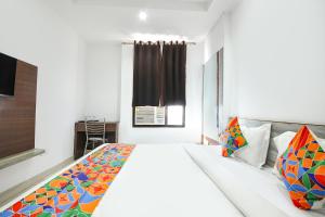 a bedroom with a large white bed with colorful pillows at FabHotel Neu-Nest in Rishīkesh +28 photos