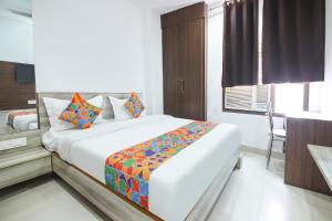 a bedroom with a large white bed with colorful pillows at FabHotel Neu-Nest in Rishīkesh